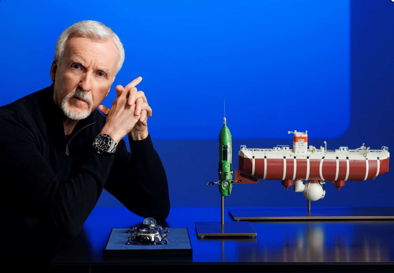James Cameron mit Modell des Tauchboots und Rolex Deepsea Challenge von 2012 und 2022